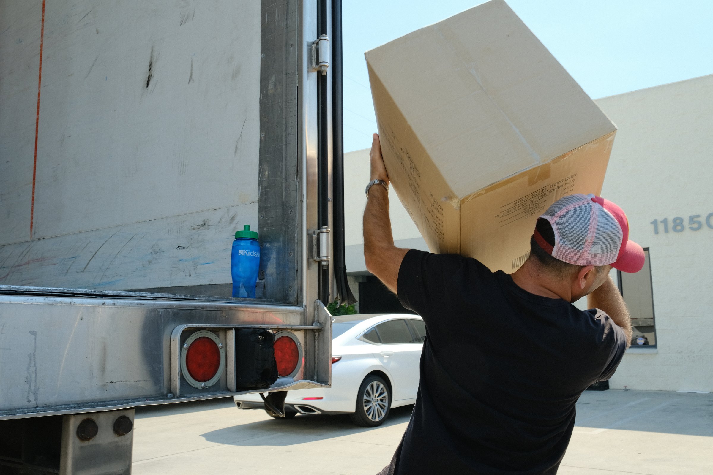 A Garni volunteer hoisting a box of relief supplies onto a truck