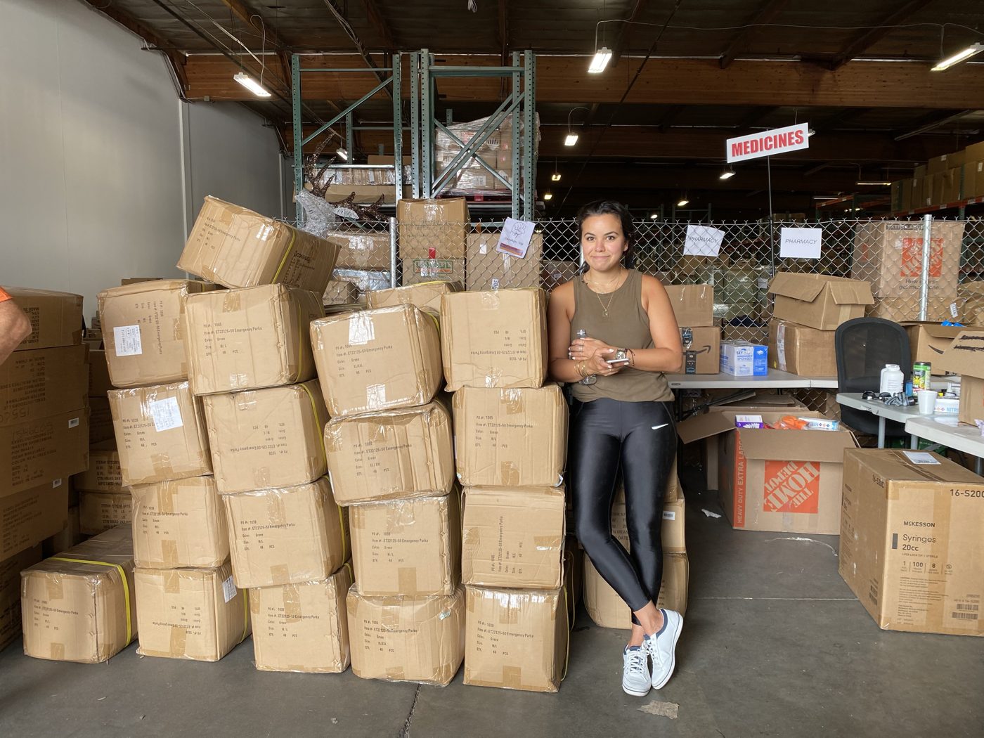 A volunteer standing with stacked relief boxes in the warehouse