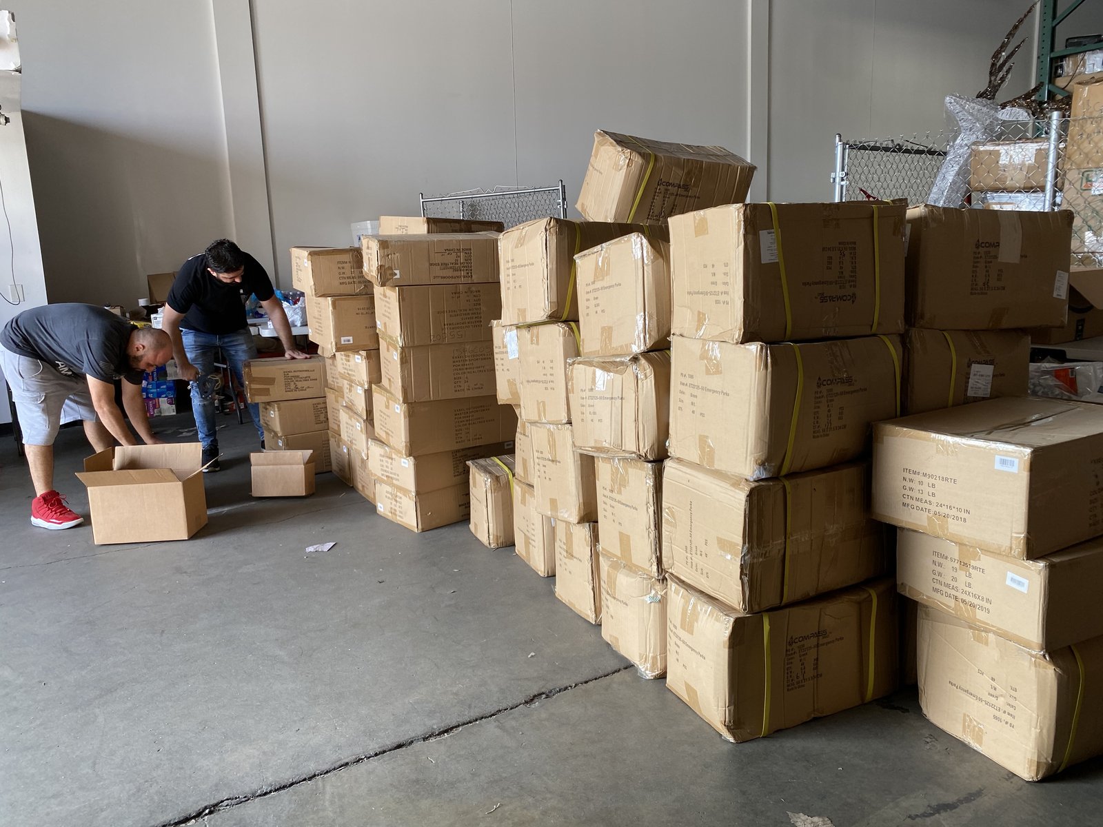 Rows of donated relief boxes in the warehouse, with volunteers sorting