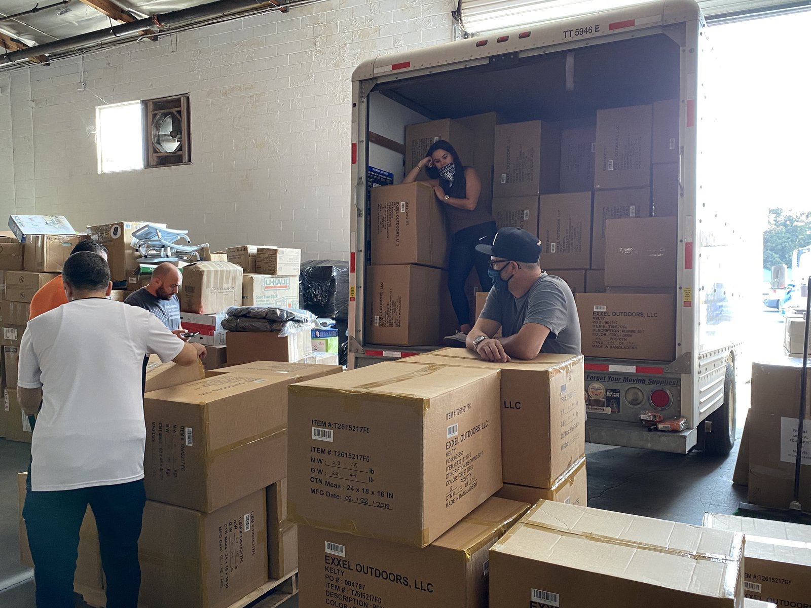 Volunteers sorting and stacking boxes in a warehouse beside a truck